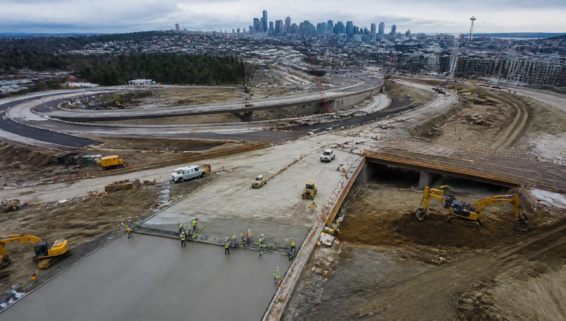 Aerial view of a Seattle highway interchange under construction with excavators and paving crews